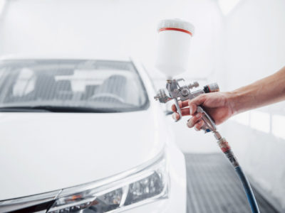 gun with paint in the hands of a man to paint a car.